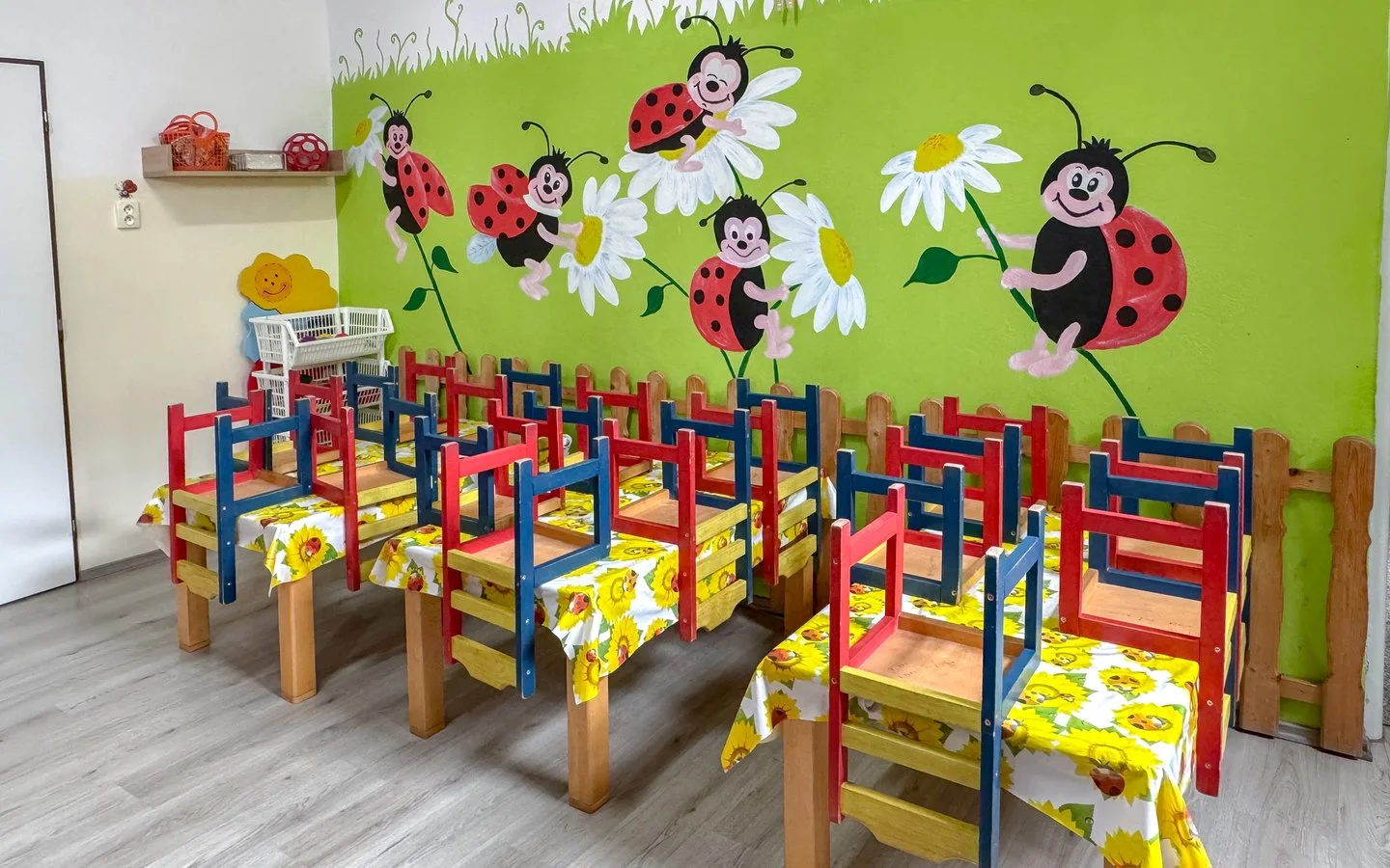 Herňa triedy Lienky — stolíky so stoličkami a maľba lienok na stene